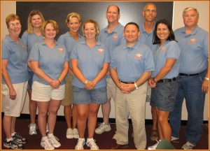 Group photo of men and women in identical blue polo shirts